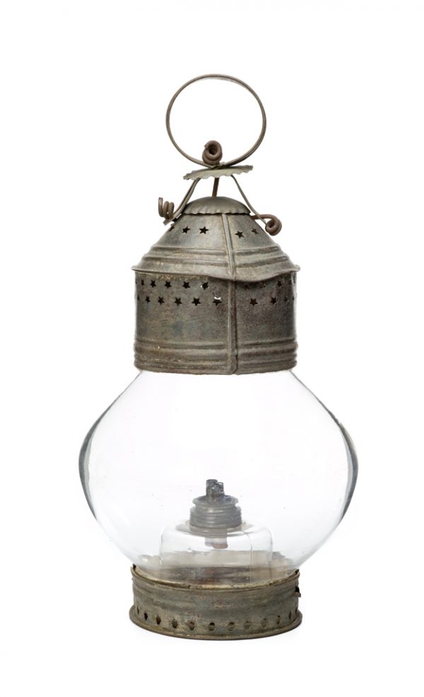 A whale oil lamp of blown glass, and tin base and top. The top has punched stars, loop tin handle and the glass has a bulbous (onion) shape.