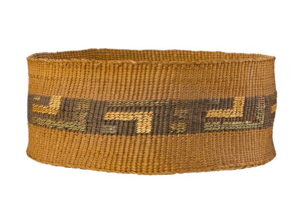 Tightly woven winned plant fiber basket with straight sides. Wrapped fibers are undyed and with areas of green and grey dyed colors creating a geometric pattern.