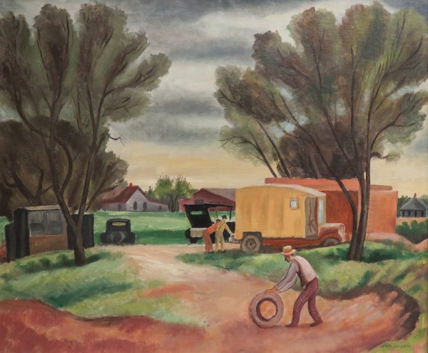 A man in the right foreground, rolls a truck tire on a dirt road leading toward two more men leaning, at the rear of a truck van. Other cars and buildings are in the background, with trees on each side.