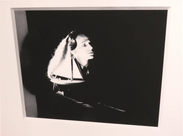 A woman wears headphones against a very dark background.