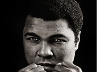 The heavyweight fighter, Muhammed Ali's face, fills the composition with just a few fingers of his fists visible along the bottom edge.