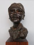 The bust of a young girl who is laughing. She wears her hair in a pony tail and is wearing earrings.