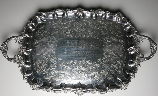 A silver plated presentation platter with acanthus leaf designs and engraved paragraph at the center and decoration giving tribute to George III or IV