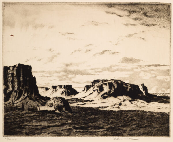 A hogan with an open door is in front of several buttes. The sky has a variety of clouds. The foreground is in shadow. Ganado is in Apache County, Arizona, and is a Chapter of the Navajo Nation.