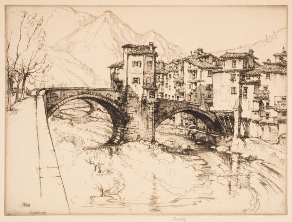 A double arched bridge is separated by a small tower. The village is to the right with mountains in the left distance.