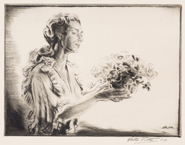 A woman holds a vase of flowers in front of her.