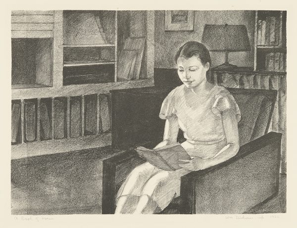 A young girl in a dress sits reading a book in an easy chair. Behind her is a lamp, bookshelves and to her right are more shelves.