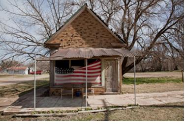 A small brick building with a U.S. flag under the front metal awning.