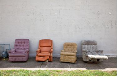 A row of multi-colored recliners are set up in front of a building.