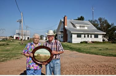 Larry Schwarm's parents, Laurence and Pauline Schwarm. They’re holding a photograph taken circa 1912 of the original house on this property. The farm was part his grandfather’s wedding present from his parents who farmed about ten miles to the south of this property.