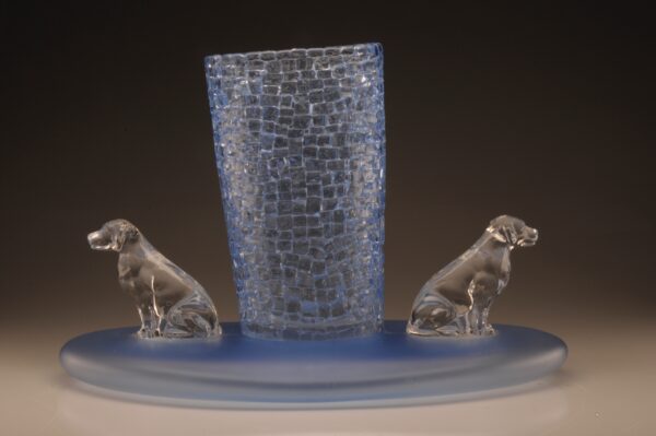 Light blue blown glass vase on an oversized circular base with clear crystal glass dogs on two sides