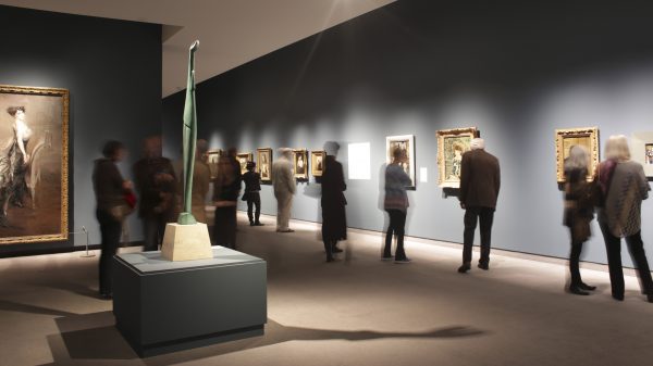 Interior view of galleries with adults looking at artwork on the wall from French Impressionist painters