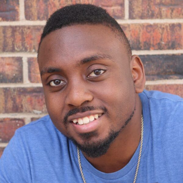 Photo of man in front of brick wall