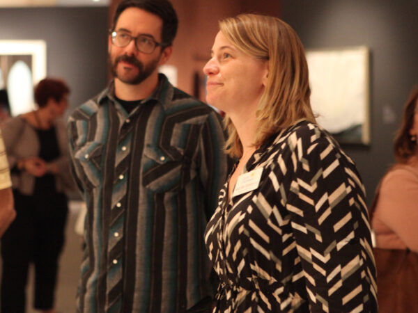 Two art educators, one woman and one man, standing sideways from the camera looking at art from the Georgia O'Keeffe exhibition
