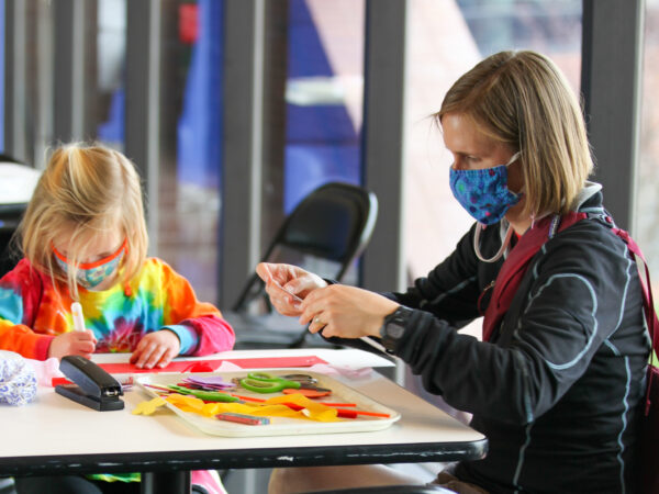 Child in tie-die shirt and adult at a table making an art project