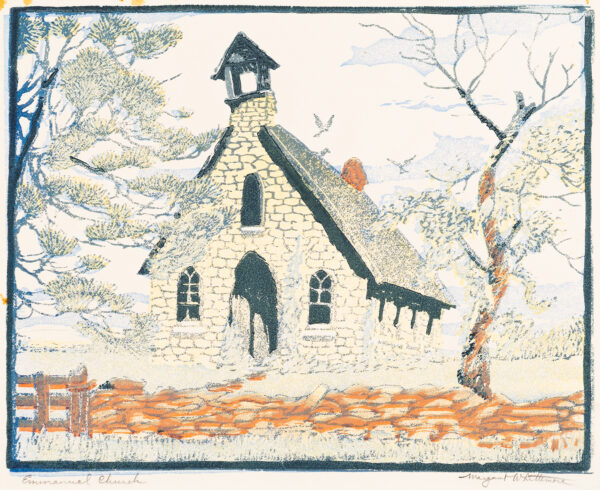 A small stone church with a bell tower has a stone fence in front with trees on each side.