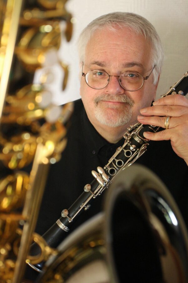 Photo of a man with white hair and short white beard holding a saxophone