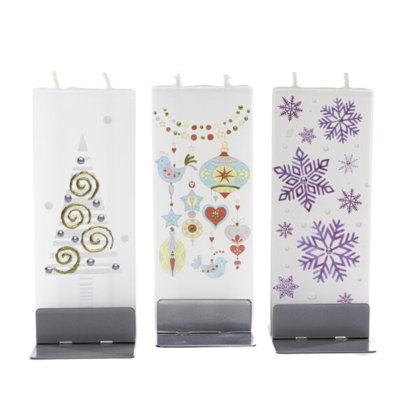 Three flat handmade candles in holiday motifs sitting in silver bases