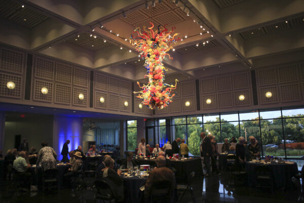 Silhouette of a group of people at tables under the brightly colored Chihuly Chandelier.