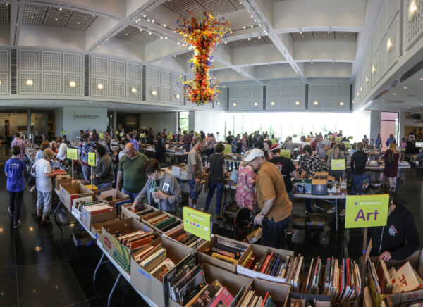 Photo of dozens of people in the S. Jim and Darla Farha Great Hall looking at hundreds of book for sale spread out over tables that fill the entire area