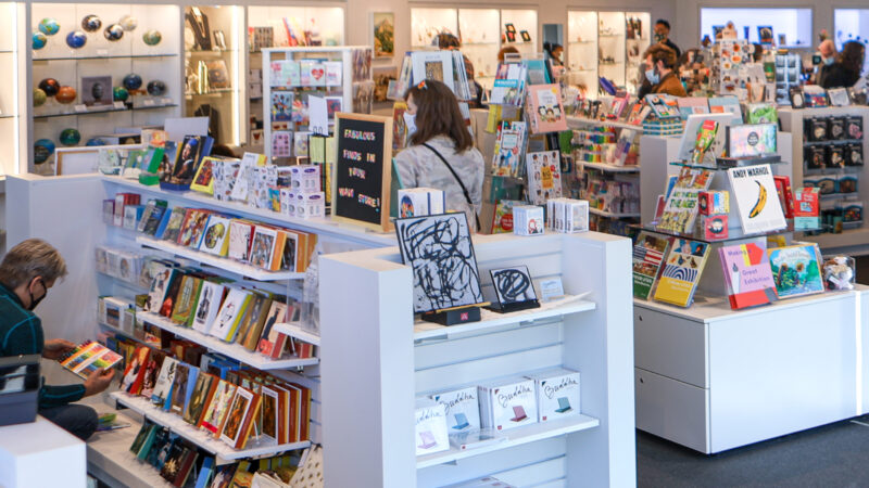 Interior photo of the Museum Store showing six aisles of merchandise with two female shoppers in the foreground