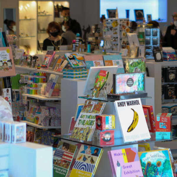 Interior photo of the Museum Store showing six aisles of merchandise with three female shoppers in the background