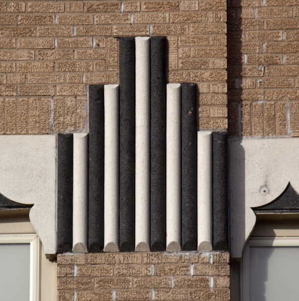 Brick column topped with a series of alternating black and white cylindrical shapes - three tall in the center, flanked on either side by two more sets in progressively shorter height.