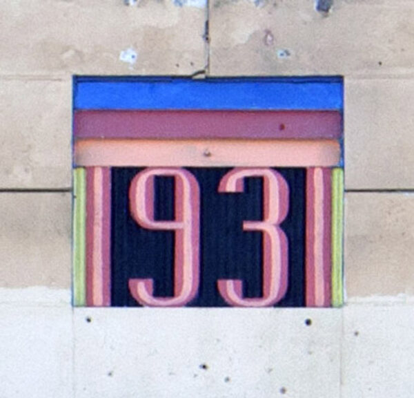 Art Deco style numbers, 1931 in white with pink/red outline, with strips of blue, dark pink, and light pink above the numbers, inset into white stone