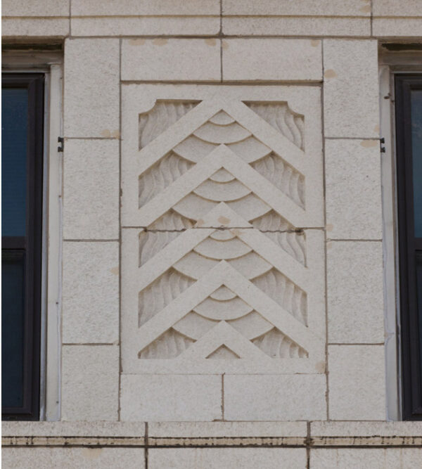 Relief sculpture in Art Deco style of repeating arrow-like objects carved in white stone