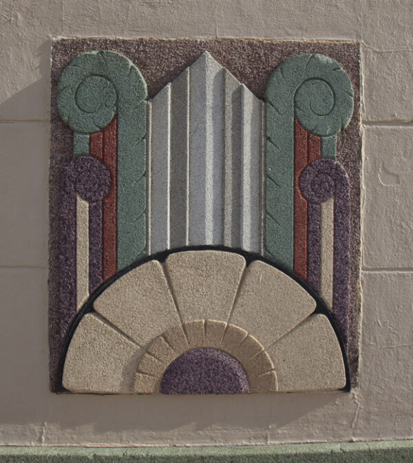 Art Deco relief sculpture of a half sunflower in white, gold and brown, with geometric swirls reaching to the top of the sculpture in green, terracotta red and brown