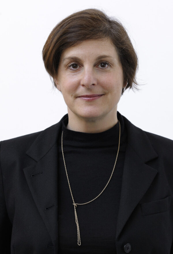 Photo of a white woman with short brown hair, brown eyes and wearing a black jacket and shirt along with a gold necklace