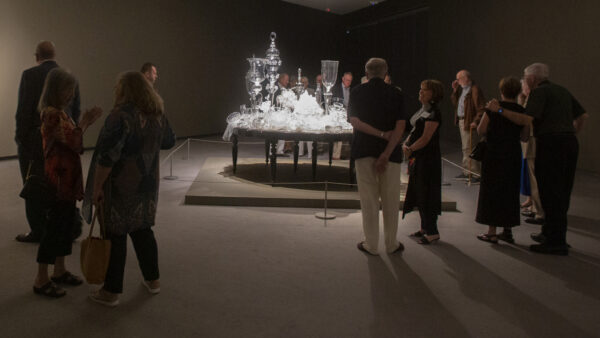 Image of a group of people in the gallery around a Beth Lipman glass scilpture, 