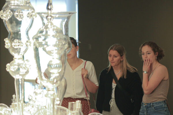 Three young women looking at a glass sculpture