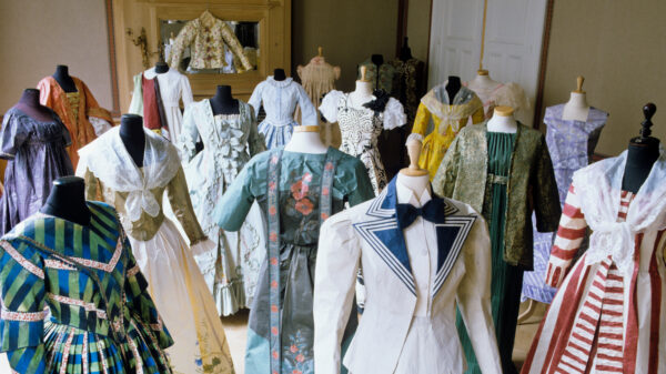 Reproductions of 18th and 19th century women's clothing displayed on headless mannequins. Seventeen garments of various styles and colors are pictured.