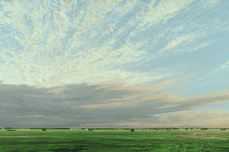 Landscape with green foreground, clouds in gray tones in the middle ground and a blue sky with wispy white clouds