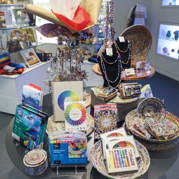 Display of colorful merchandise from the Museum Store including necklaces, notecards, baskets, markers and Christmas tree ornaments